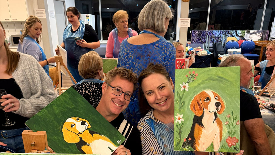 James from Paint Juicy with a guest holding finished beagle paintings at Beagle Rescue Queensland charity night Everton Park Bowls Club Brisbane