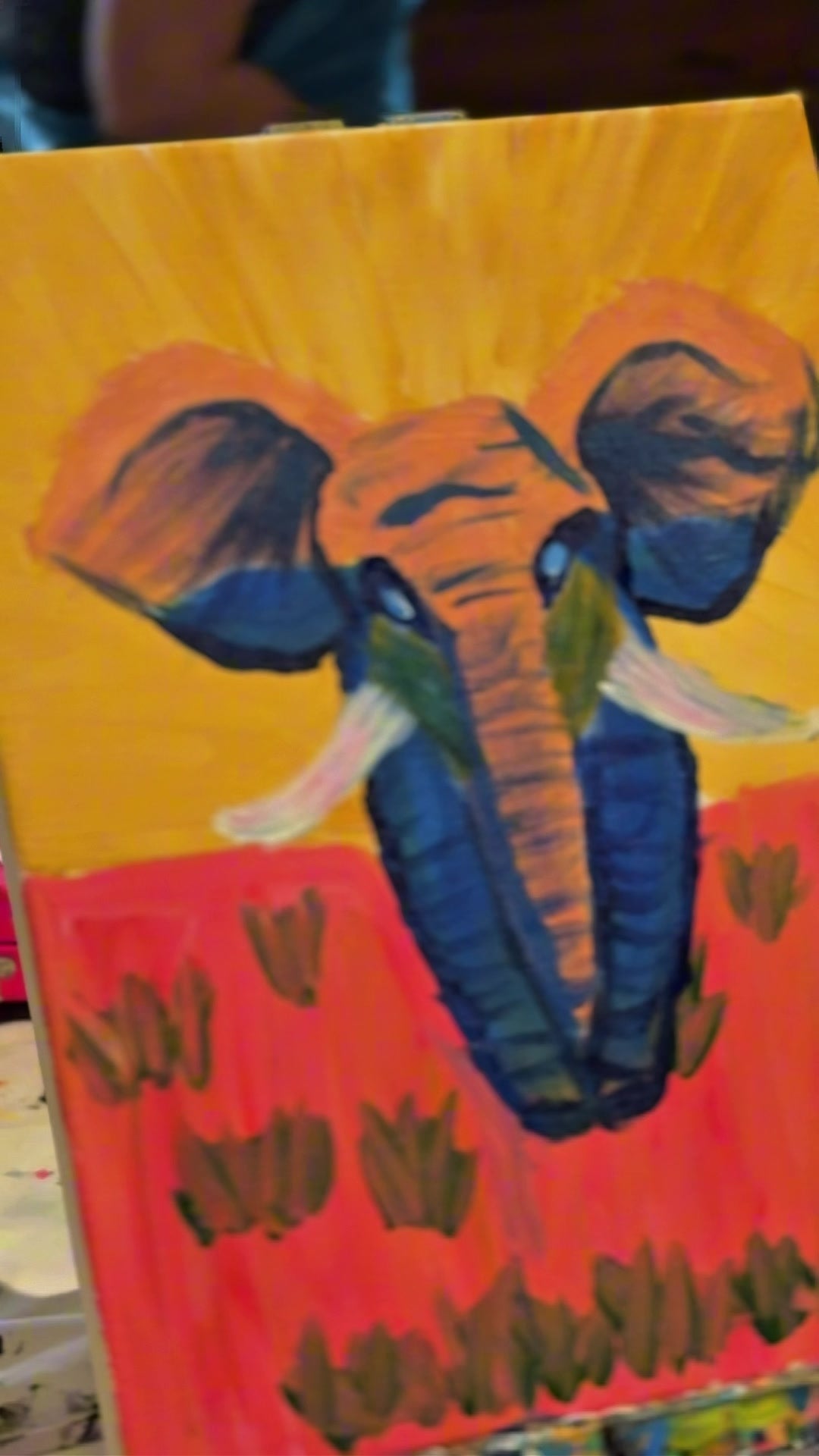 Bold blue elephant painting against an orange sunset on an easel at a Coffs Harbour team building paint and sip