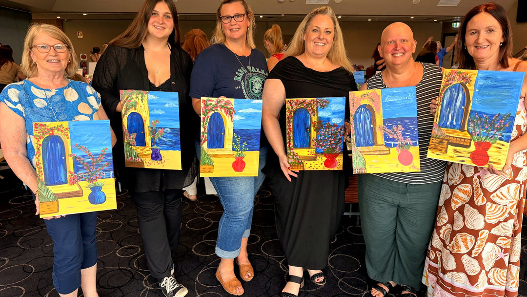 Six guests at The Davo RSL holding finished Santorini paintings with bougainvillea and lemon tree variations at a Davistown Paint Juicy session