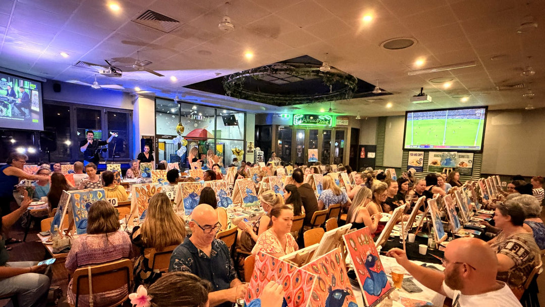 Wide shot of Palmerston Tavern Paint and Sip in full swing with David singing on stage and a packed room of painters working on peacock canvases