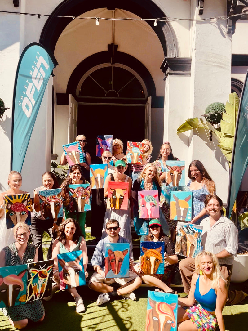 people holding artworks on top of each other in rows