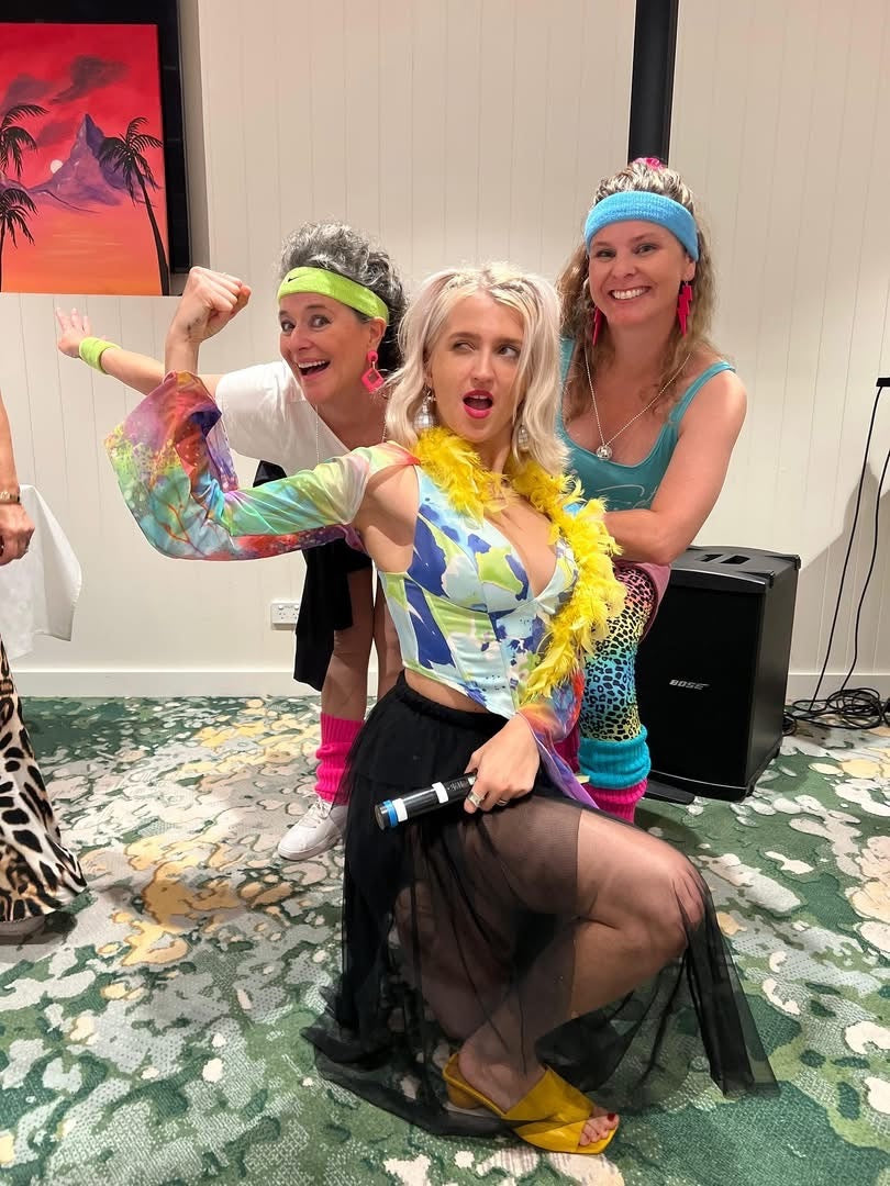 Three people in colorful costumes posing for a photo on a patterned floor.