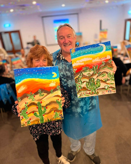 Paint Juicy guests holding their finished Prick My Interest cactus paintings at a paint and sip night, photo 1 of 6