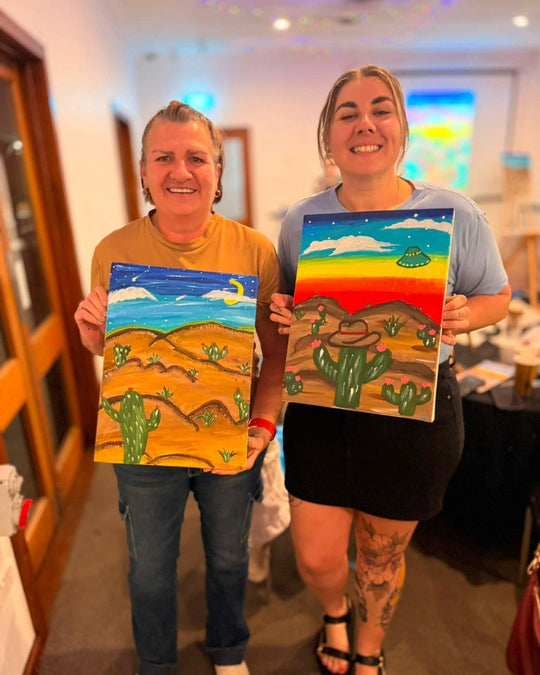 Paint Juicy guests holding their finished Prick My Interest cactus paintings at a paint and sip night, photo 2 of 6