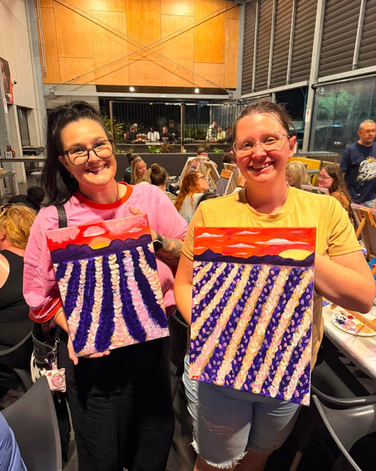 Paint Juicy guests holding their finished Lavender Fields paintings at a paint and sip night, photo 1 of 5