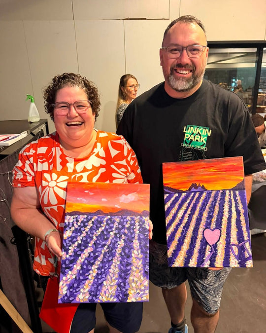 Paint Juicy guests holding their finished Lavender Fields paintings at a paint and sip night, photo 4 of 5