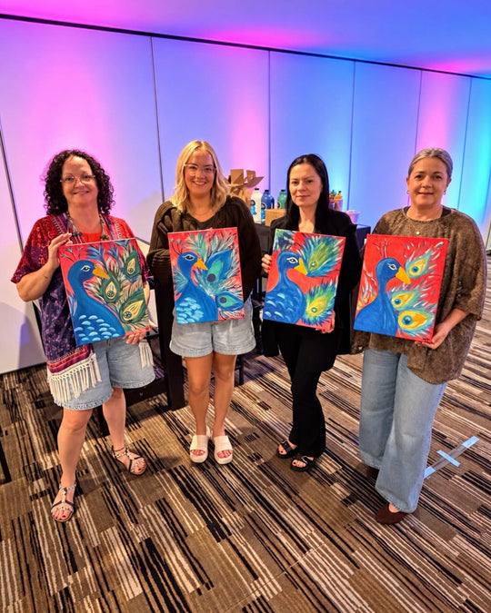 Paint Juicy guests holding their finished The Red Peacock paintings at a paint and sip night, photo 2 of 4