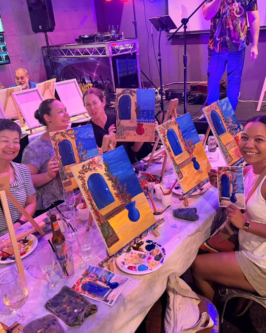Paint Juicy guests holding their finished Santorini Door paintings at a paint and sip night, photo 1 of 6