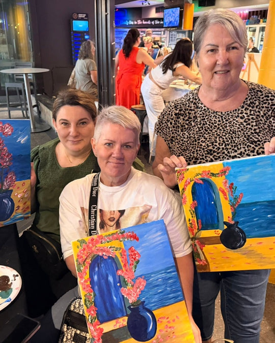 Paint Juicy guests holding their finished Santorini Door paintings at a paint and sip night, photo 4 of 6