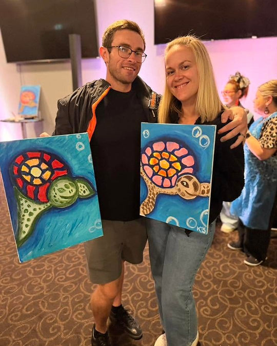 Paint Juicy guests holding their finished Sea Turtle paintings at a paint and sip night, photo 2 of 6