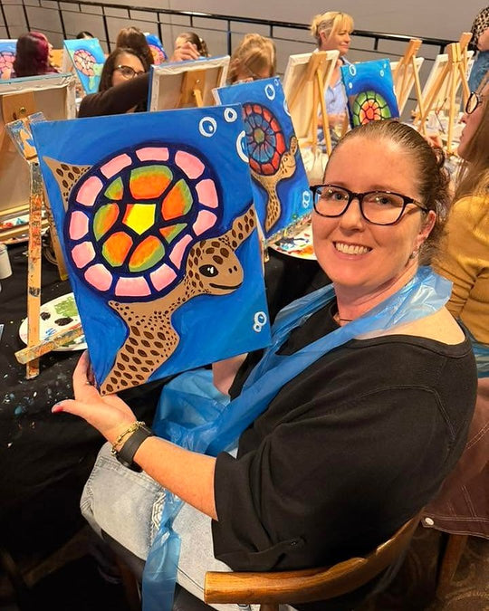 Paint Juicy guests holding their finished Sea Turtle paintings at a paint and sip night, photo 3 of 6