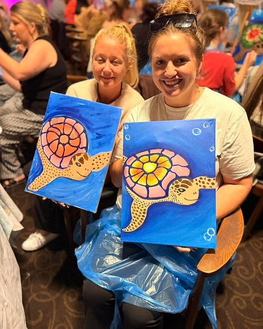 Paint Juicy guests holding their finished Sea Turtle paintings at a paint and sip night, photo 4 of 6