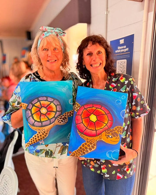 Paint Juicy guests holding their finished Sea Turtle paintings at a paint and sip night, photo 5 of 6