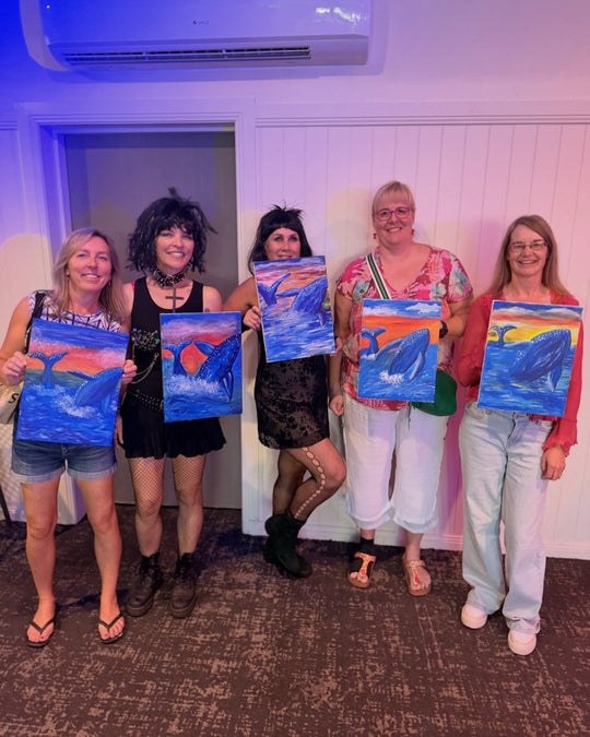 Paint Juicy guests holding their finished Ocean Whale paintings at a paint and sip night, photo 1 of 6