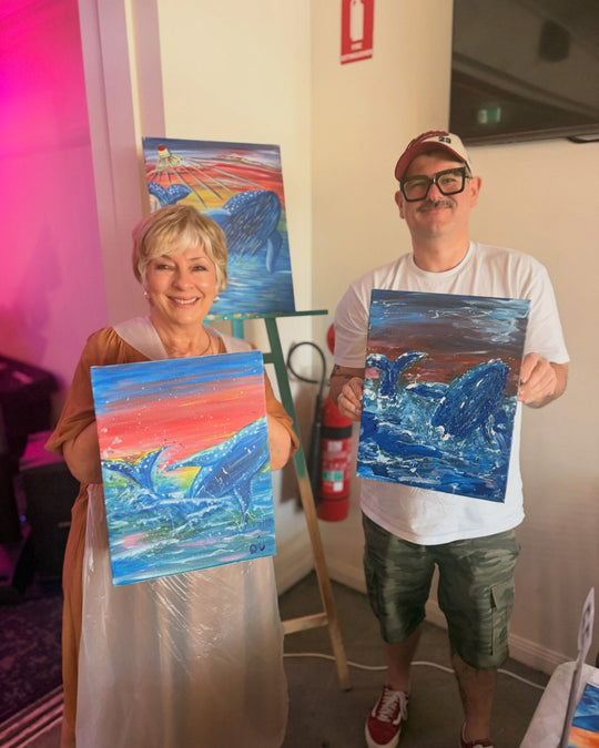 Paint Juicy guests holding their finished Ocean Whale paintings at a paint and sip night, photo 2 of 6
