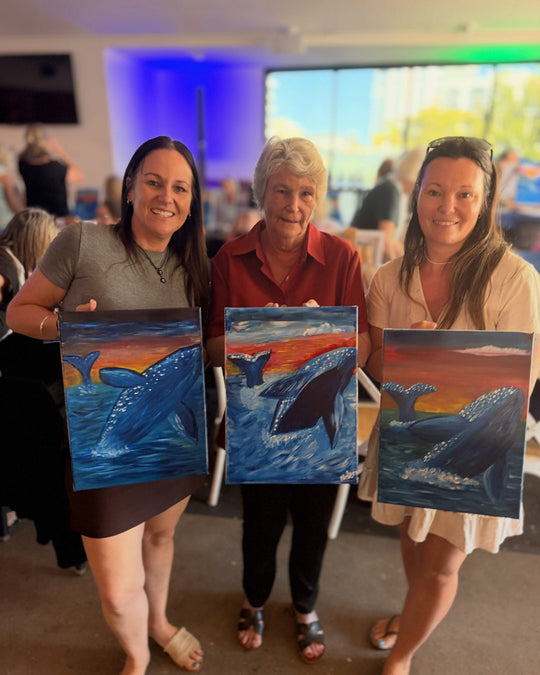 Paint Juicy guests holding their finished Ocean Whale paintings at a paint and sip night, photo 3 of 6